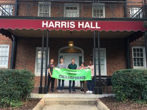 Students hold a banner outside Harris Hall as champions of the energy saving competition between the residence halls